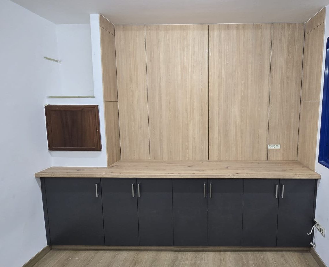 Mueble a medida con panel de madera y módulos bajos en gris antracita, instalado por Carpintería Coruxo